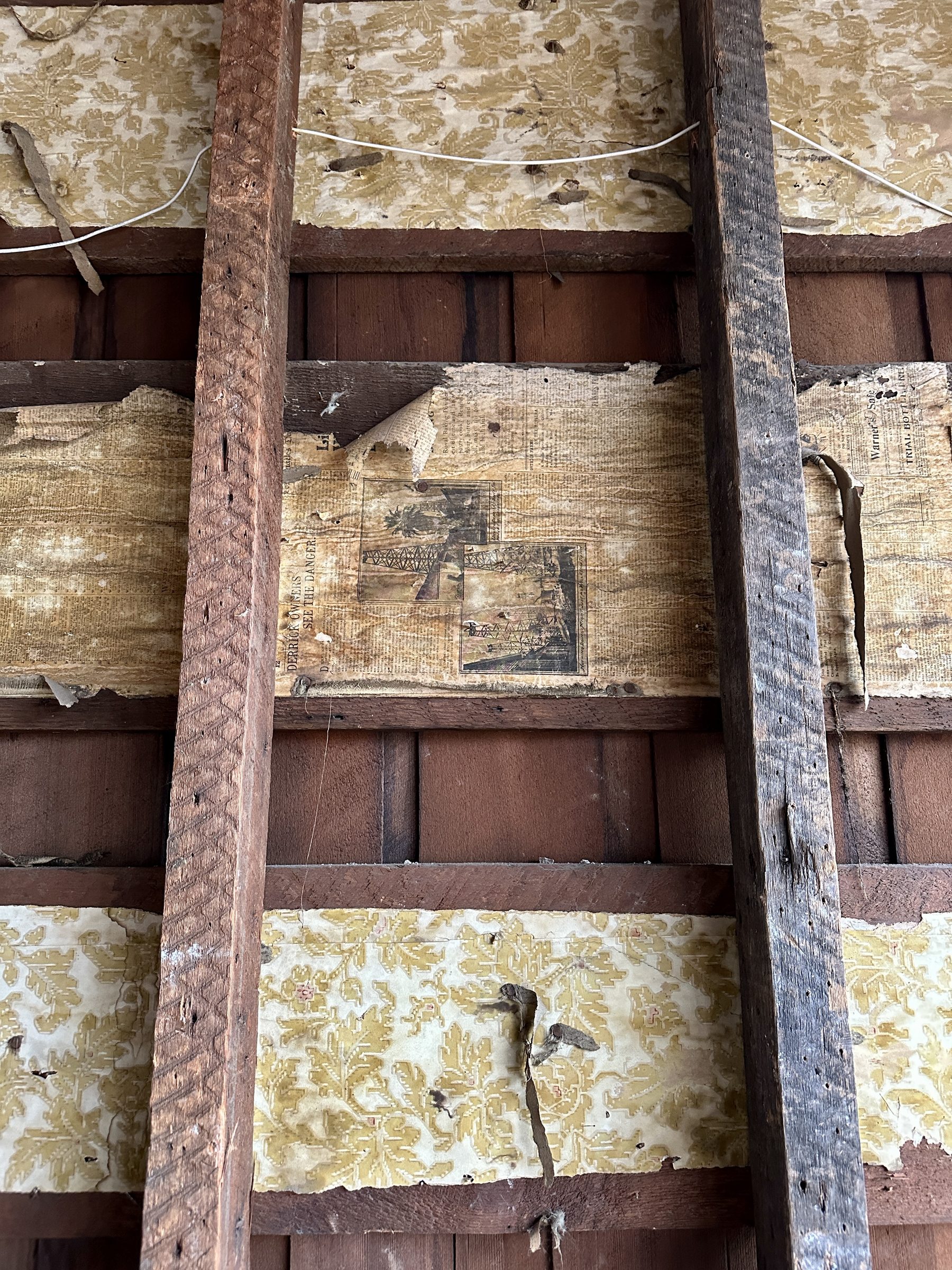 Closeup of framing with original wallpaper and newspaper clippings from 1902