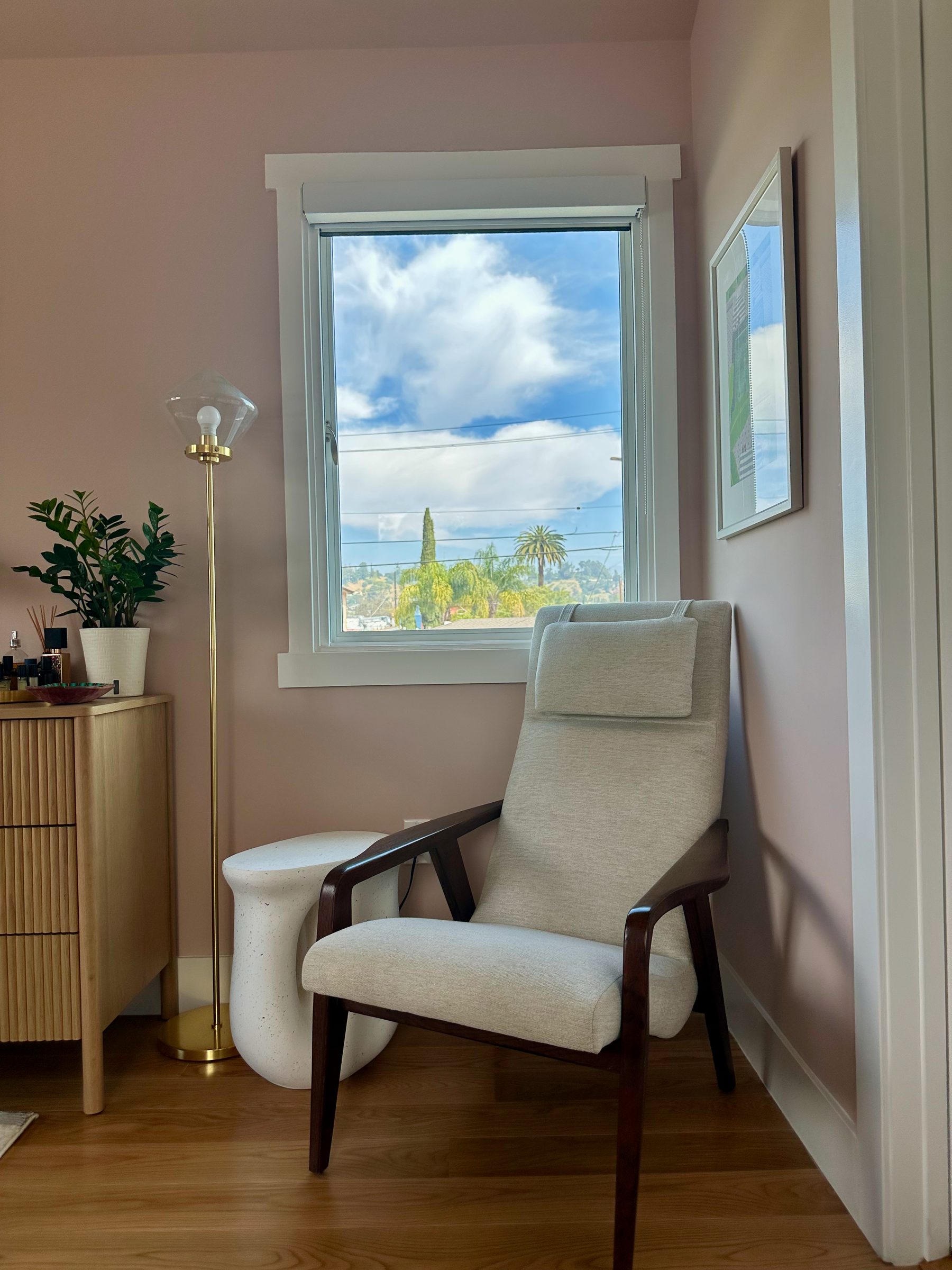 Reading corner with mid-century chair, brass lamp, and hillside views