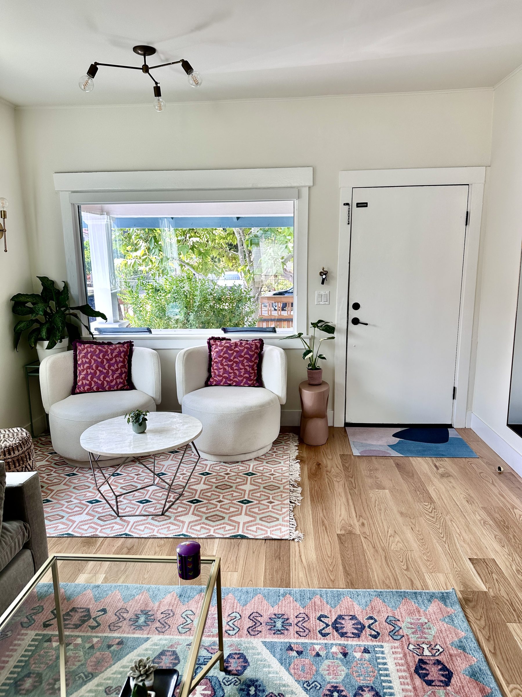 Renovated living room with cream swivel chairs and layered rugs