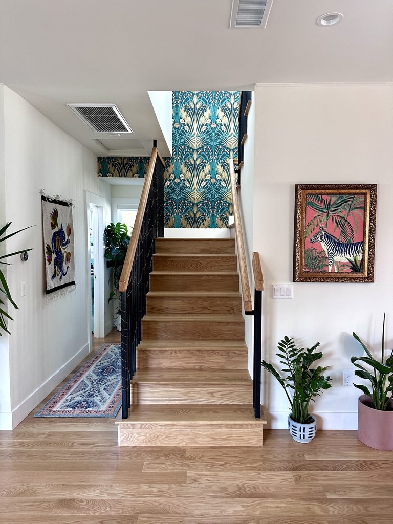 Staircase from the front with botanical wallpaper, zebra painting, and oak treads